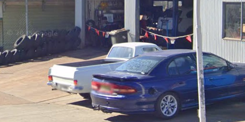 Cars parked in the yard at Alex Ross Automotive with the workshop bays open behind them